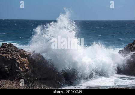 Grande onda che si schiantano contro le rocce vulcaniche a Lanzartote, Isole Canarie. Foto Stock