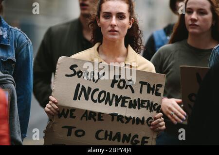 Donna che protestava con un gruppo di persone in viaggio. Gruppo di attivisti che marciano e protestano in città. Foto Stock