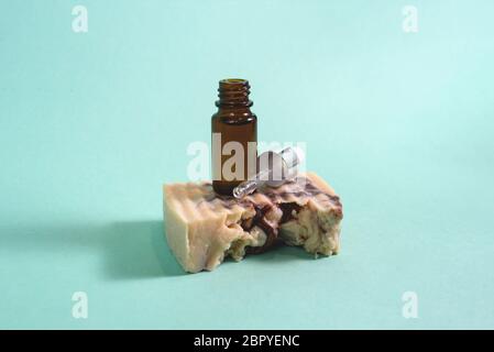 Un flacone contagocce in vetro aperto su zuppa naturale fatta a mano su sfondo verde o menta. Concetto di pelle naturale. Cosmetici biologici Spa. Primo piano. Foto Stock