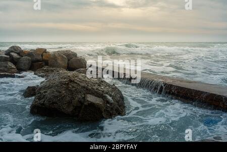 Onde schiumose si schiantano sulla costa rocciosa Foto Stock