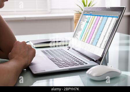 Close-up di un imprenditore la mano esaminando i rapporti sul computer portatile in ufficio Foto Stock