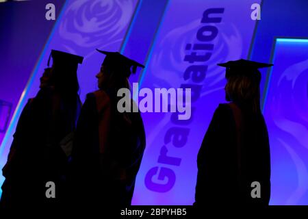 Tre studenti in abiti neri e cappelli durante la giornata di laurea all'università. Foto Stock