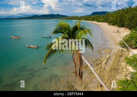Vista aerea di una splendida spiaggia tropicale vuota circondata da palme con piccole barche da pesca in legno Foto Stock