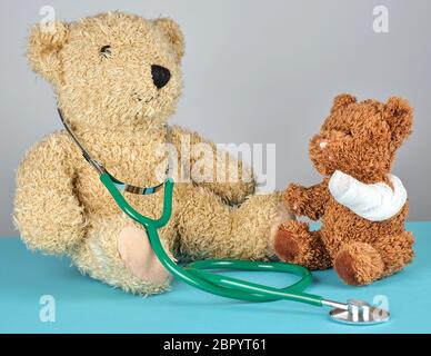 Orsacchiotto di peluche con zampa bendato e stetoscopio, pediatria nozione Foto Stock