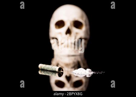 La cocaina o altre droghe illegali che vengono rilevati per mezzo di un tubo e il cranio, isolato su nero sfondo lucido Foto Stock
