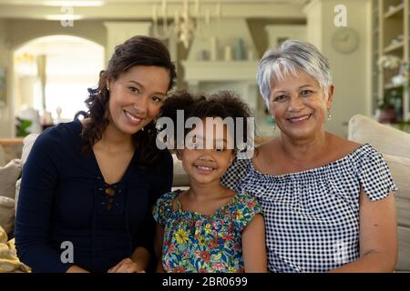 Donna mista da corsa con la madre più anziana e la figlia più giovane che guarda la macchina fotografica Foto Stock