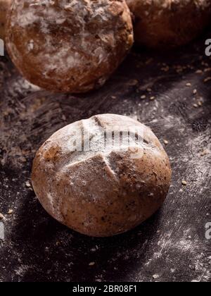 Primo piano le focacce rustiche di pane poste su sfondo nero di legno. Foto Stock