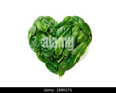 Forma del cuore fatta da foglie di spinaci. Modello spinaci isolato su bianco con tracciato di ritaglio. Layout creativo da foglie perfette fresche di spinaci - h Foto Stock