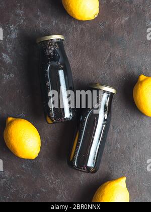 Detox carbone attivo nero acqua chia o limonata con il limone. Due bottiglie di nero chia infusa l'acqua. Detox drink idea e ricetta. Cibo Vegan un Foto Stock