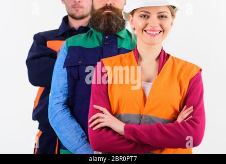 Concetto leader femminile. Donna con volto felice si trova davanti agli uomini in uniforme. Team di architetti, costruttori, isolato sfondo bianco. Costruttore, ingegnere, lavoratore, riparatore come amichevole squadra. Foto Stock