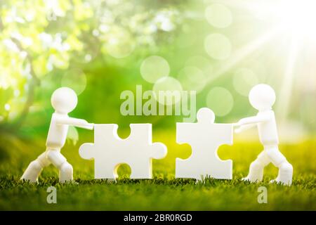 Due figure umane risolvendo i puzzle su erba verde Foto Stock