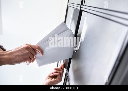 Basso Angolo di visione della persona mano inserire le buste nella cassetta postale Foto Stock