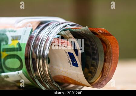Composizione con banconote di risparmio in un vaso di vetro. Concetto di investimento e di mantenimento del denaro, primo piano isolato. Foto Stock