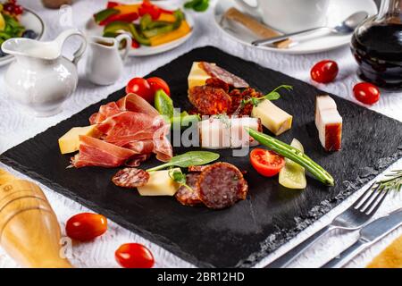 Varietà di salumi, salsicce e bacon servita su una scheda di ardesia presso il ristorante in tabella Foto Stock