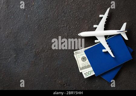 Modello di aeroplano, due passaporti e soldi su uno sfondo scuro. Concetto di viaggio. Lay piatto con copia spazio. Foto Stock