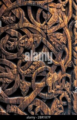 Ornamenti di antichi vichinghi su una superficie di legno. Esterno la parete in legno decorazioni scolpite della doga medievale chiesa con motivi viking coperti con tar. Foto Stock