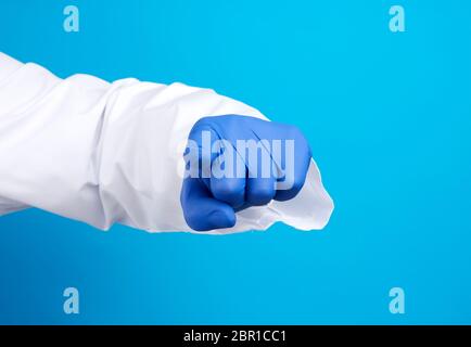 mano del medico in guanto blu in lattice e camice bianco, l'indice si allunga in avanti, imitazione della pressione di puntamento, sfondo blu Foto Stock