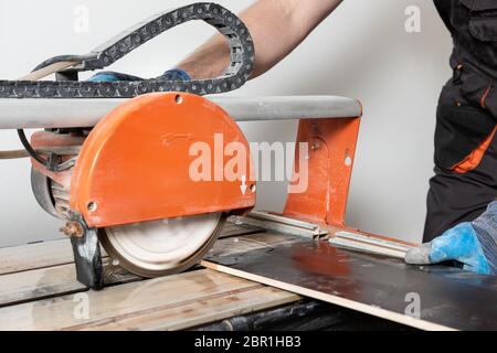 Un lavoratore sta tagliando una piastrella ceramica su una macchina di taglio a umido. Foto Stock