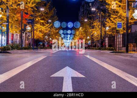 30 Novembre 2019 - Granada, Spagna. Una strada a tre corsie su Calle Gran Via de Colón. Ornamenti di Natale appesi sulla strada e alberi con lea giallo Foto Stock