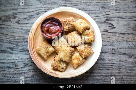 Piastra con ravioli fritti sulla tavola di legno Foto Stock