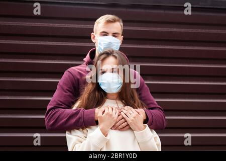 Giovane coppia spaventata abbracciando una maschera di protezione del viso in città dal nuovo Coronavirus Covid 19 Foto Stock