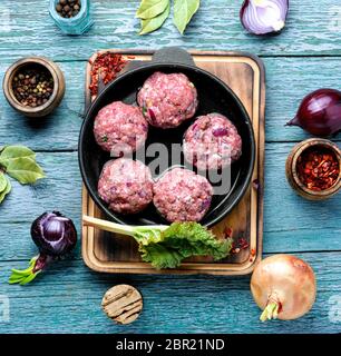 Polpettine di carne di manzo crudo forza-carni in ghisa pan Foto Stock