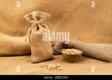 Soy fagioli in un sacco e in una ciotola di legno su sacco. Foto Stock