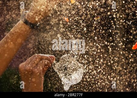 Mano di ragazza con spruzzi d'acqua su sfondo nero filtro scuro stile Foto Stock