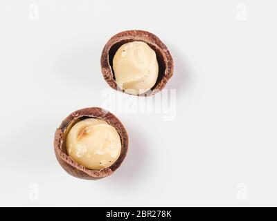 Due noci di macadamia sbucciate su sfondo bianco. Set di due dadi in macadamia con conchiglie aperte, isolati su bianco, vista dall'alto o piatto. Spazio di copia per tex Foto Stock