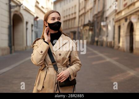 Donna che indossa abiti alla moda durante la quarantena di focolaio di coronavirus. Modello vestito protettivo elegante maschera fatta a mano. Walkin turistico on Foto Stock