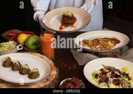 La cameriera porta sano cibo vegetariano. Insalata di barbabietole con pomodori secchi e cavolo, Potato Pancake vegan, pomodori secchi, pate dal rosso bea Foto Stock