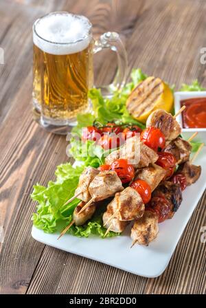 Grigliate gli spiedini di pollo con la tazza di birra Foto Stock