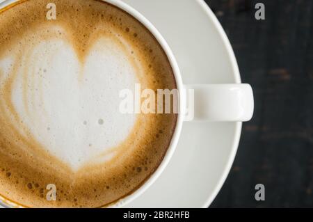 Flatlay metà forma di cuore Latte Latte Art in bianco con tazza di caffè nero sulla tavola di legno. Forma di cuore Latte Latte Art bevanda calda per amante del caffè Foto Stock