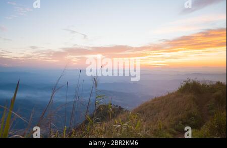 Oro la luce del tramonto con la montagna e il cielo blu e l'erba campo al crepuscolo. Twilight paesaggio Phu Nom di Phu Langka Parco Nazionale della Thailandia. Thailandia Tr Foto Stock