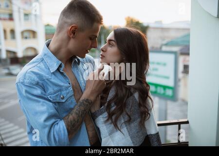 In piedi sul balcone, hugging, momenti teneri. Quarantena, soggiorno casa concetto - bella coppia caucasica godendo di nuovo stile di vita durante coronavirus. Felicità, togetherness, sanità. Foto Stock