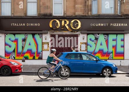 Shawlands, Glasgow, Scozia, Regno Unito. 20 Maggio 2020. Poiché le nuove piste ciclabili sono tra le misure di emergenza messe in atto per rendere le città più ciclabili per ridurre la dipendenza dai trasporti pubblici durante la pandemia del coronavirus, un ciclista passa un segno 'sicuro' negli Shawlands, Glasgow Credit: Kay Roxby/Alamy Live News Foto Stock