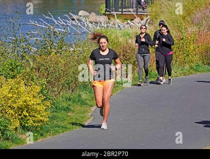 Un gruppo di giovani donne pratica sociale distancing becuse del virus Covid 19 come corrono lungo il fiume Deschutes a Bend, Oregon. Foto Stock