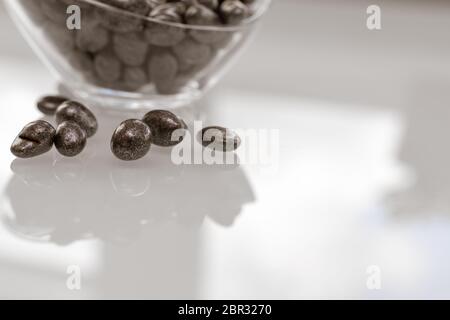 uvetta in cioccolato in un recipiente di vetro su una superficie lucida e leggera Foto Stock