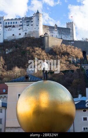 SALISBURGO, AUSTRIA - 10 MARZO 2019 : scultura di un uomo su una sfera d'oro di Stephan Balkenhol su Kapitelplatz, Fortezza di Hohensalzburg Foto Stock