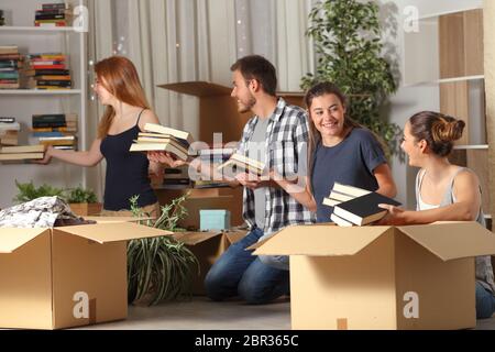 Quattro felice coinquilini cooperanti belingings di inscatolamento di casa mobile nella notte Foto Stock