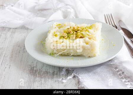 Pasto tradizionale turco - Gullac. Dessert al latte cosparso di noci e pistacchi macinati. Piatto Ramadan Foto Stock
