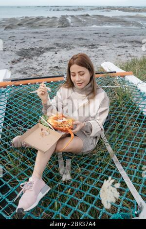 Bella donna asiatica che tiene un artiglio di aragosta o gamberi all'aperto con bella luce del sole sulla barca a vela sulla spiaggia Kaikoura, Nuova Zelanda. Foto Stock