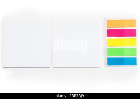 Due note bianche adesive e diversi fogli colorati di carte da note isolate su sfondo bianco. Foto Stock