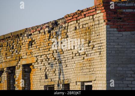 Vecchio mattone sovietica edificio abbandonato. Collassare costruzione in mattoni. Il bianco e il rosso mattone Foto Stock