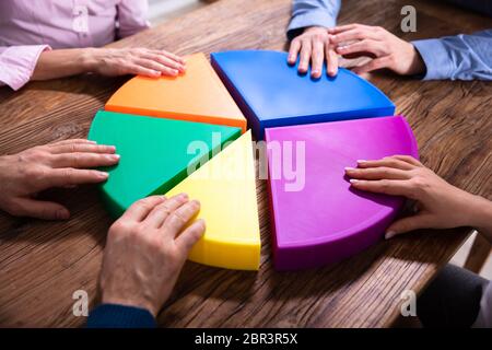 Gli imprenditori pezzi di collegamento di multi colore grafico a torta sulla scrivania in legno Foto Stock