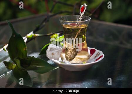 Tè turco alla mela e dolci (delizie turche), serviti su un tavolo di vetro in un giardino Foto Stock