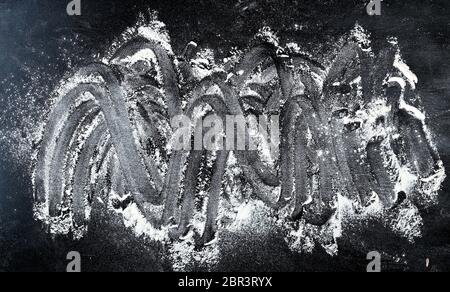 La farina di frumento bianca sparsi su uno sfondo nero, il prodotto viene steso sulla superficie, cucina sfondo, vista dall'alto Foto Stock