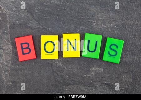 Concetto di Bonus - plastica colorata lettere su sfondo scuro Foto Stock