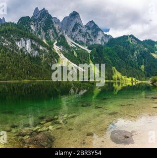 Splendido paesaggio del lago Gosausee con montagne Dachstein, foresta, nuvole e riflessi in acqua nelle Alpi austriache. Regione del Salzkammergut. Foto Stock