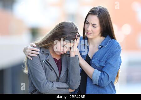 Preoccupato donna consolante il suo triste amico che si lamenta per la strada Foto Stock